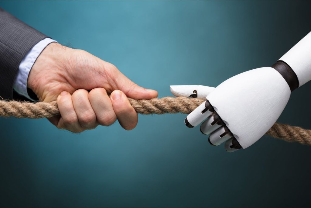 A businessperson and a robot pull a rope in a tug of war against a blue background, symbolizing the struggle between human labor and automation.