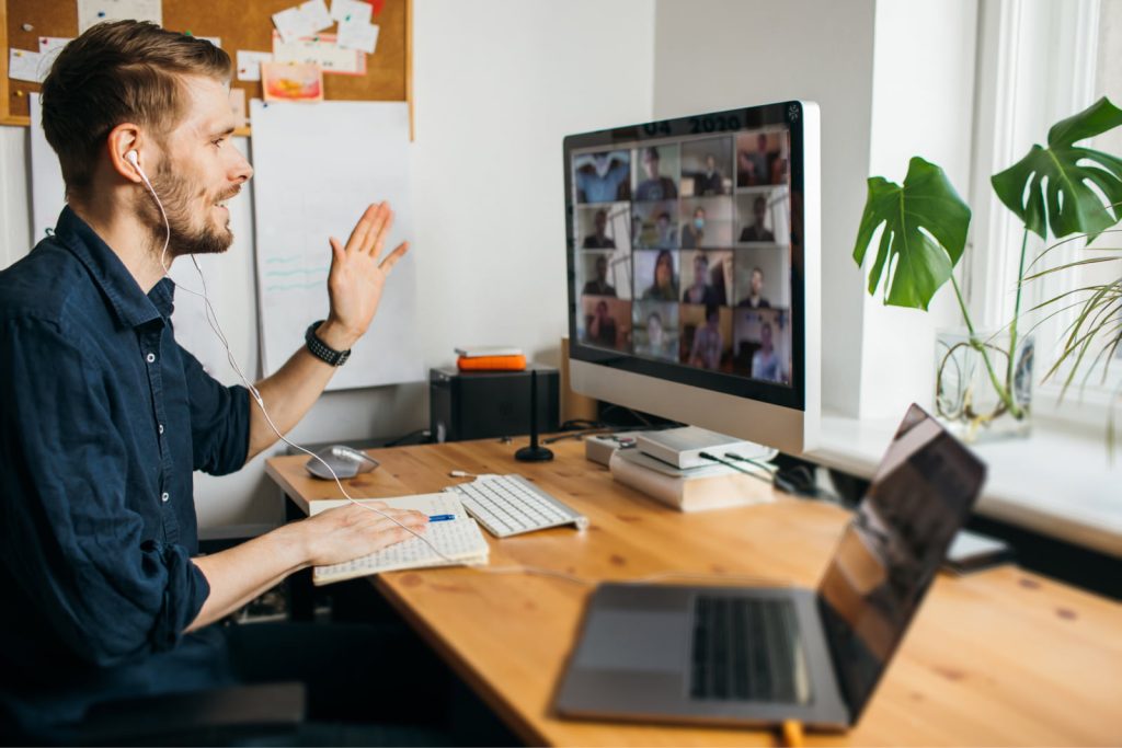 Young man having a video call from his home office, connecting with a multiethnic business team.