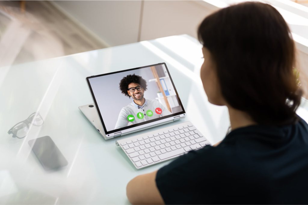 Woman seen from the back on a virtual call with a man during an online video conference.