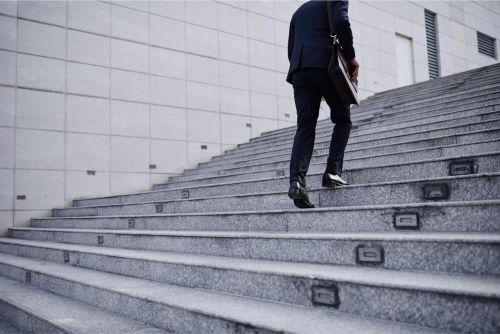 A businessperson walking up the stairs in a professional setting.