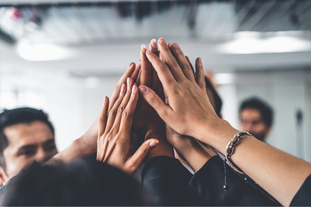 Close-up of professionals' hands coming together in a circle, symbolizing teamwork, celebration, and unity.