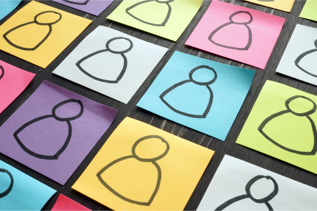 Silhouettes of diverse people on colorful sheets laid out on a table, representing diversity and inclusion.