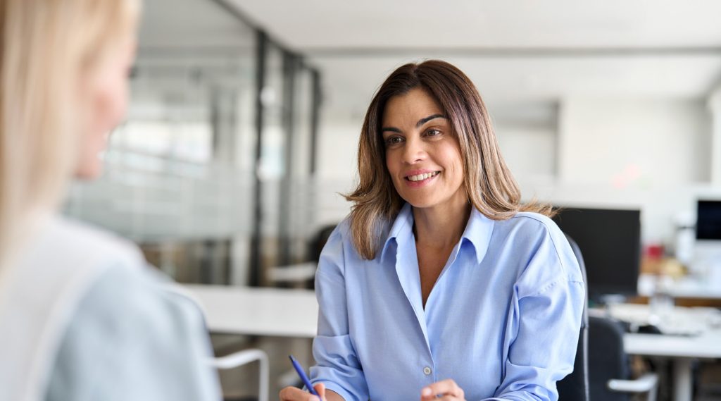 Happy middle-aged businesswoman HR talking to a recruit at a job interview in a corporate office