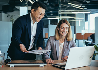 Two professionals reviewing documents and working on a laptop, symbolising effective strategies in Japanese talent solutions.