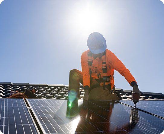 A technician installing solar panels on a roof under the bright sun, symbolising clean energy innovation.