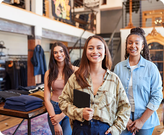 Three smiling retail employees standing in a store, symbolising a collaborative and diverse workplace.