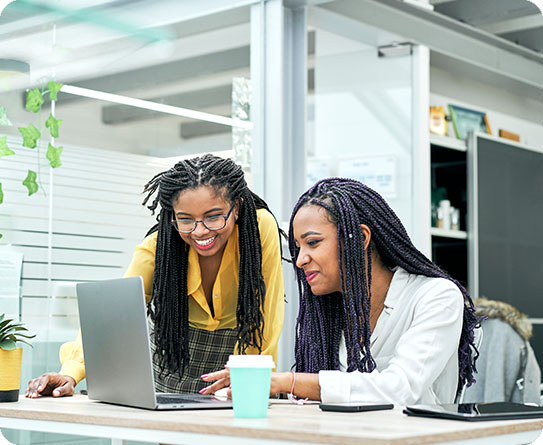 Two IT professionals collaborating on a laptop in a vibrant office space, representing teamwork and innovation.