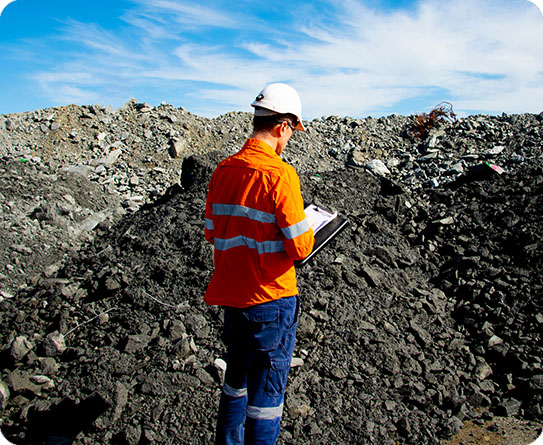 A mining professional in high-visibility gear writing notes on-site, showcasing expertise in resource extraction and site management.