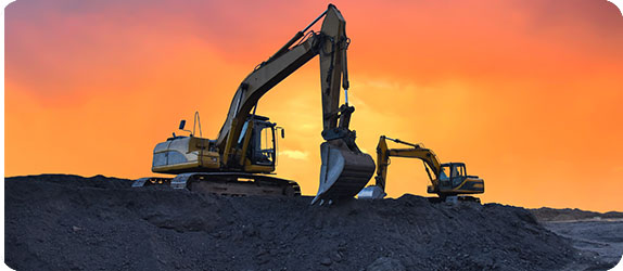 Excavators working at a mining site during sunset, showcasing machinery used in resource extraction.