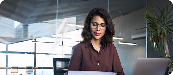 A focused sales professional reviewing reports in a modern office environment, highlighting dedication and analytical skills.