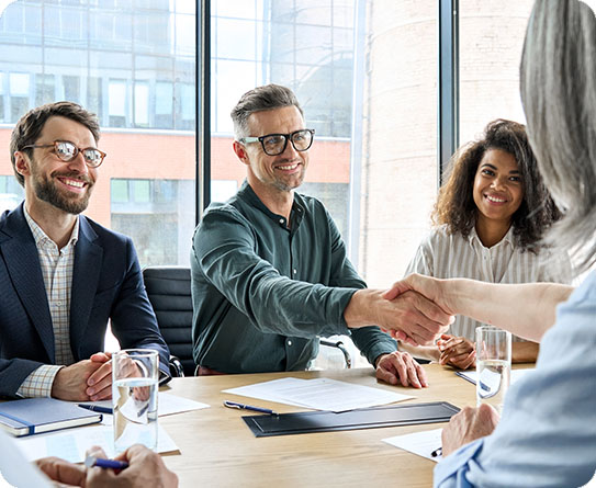 Business professionals in a meeting, shaking hands to finalize a sales agreement.