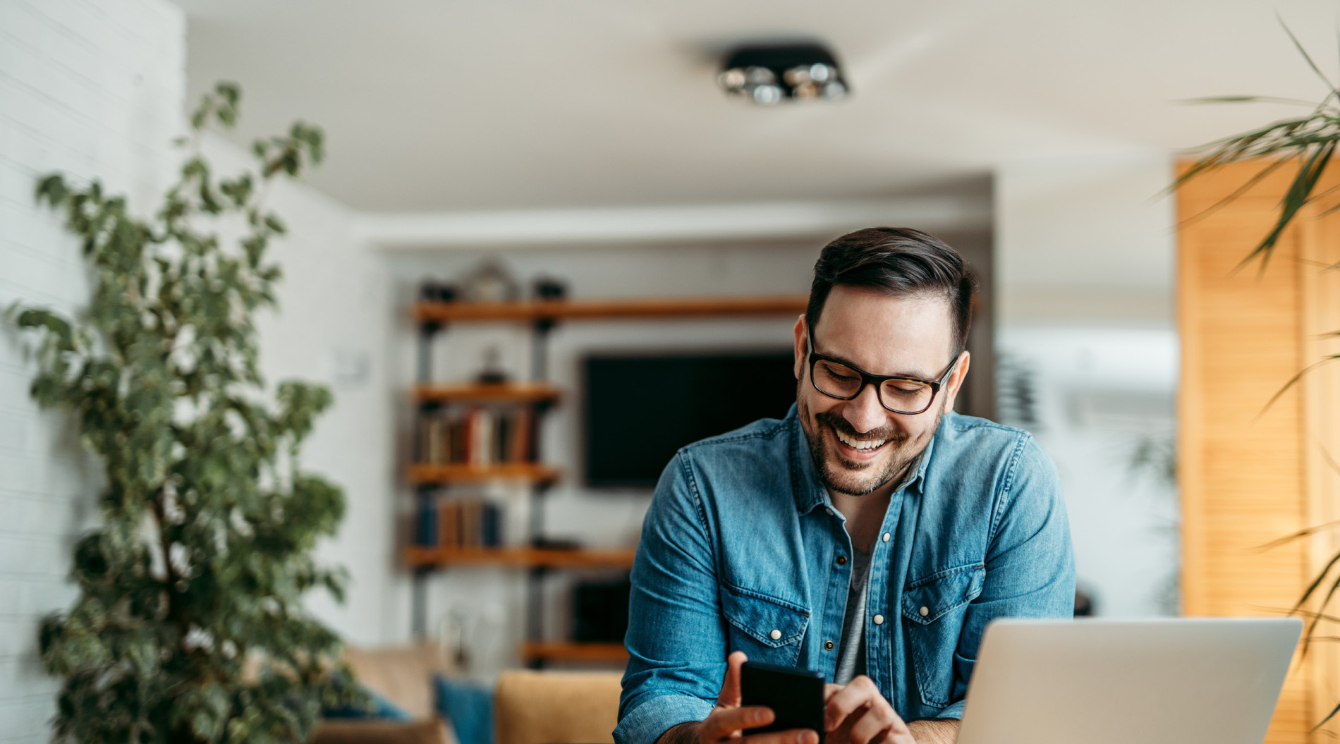 A man working from home, he is happy becuase his employer follows a balanced approach to work from home policies.