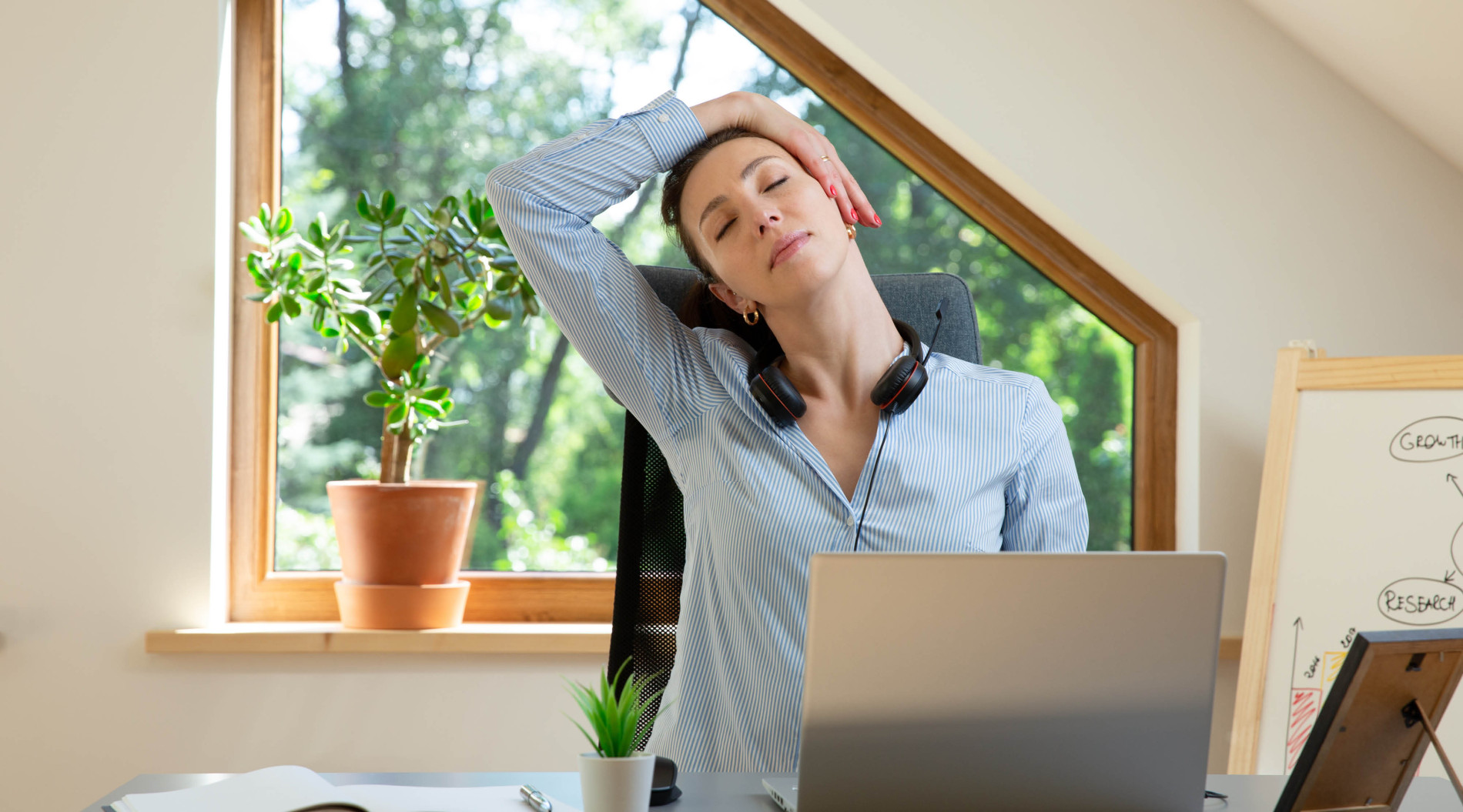 Woman stretching while working at home in front of her computer.