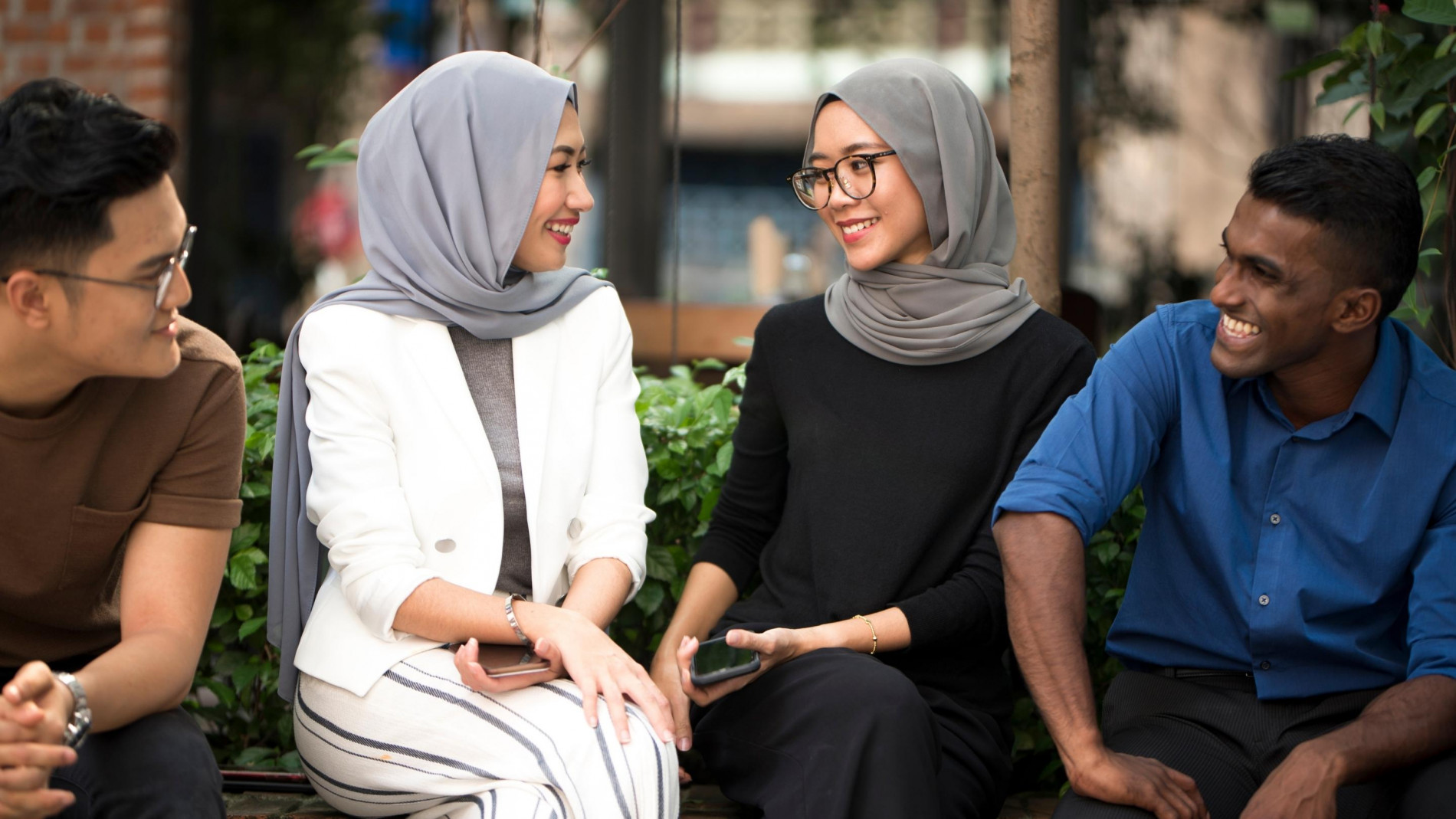 A group of multiracial, 2 women and 2 men engaging a conversation,