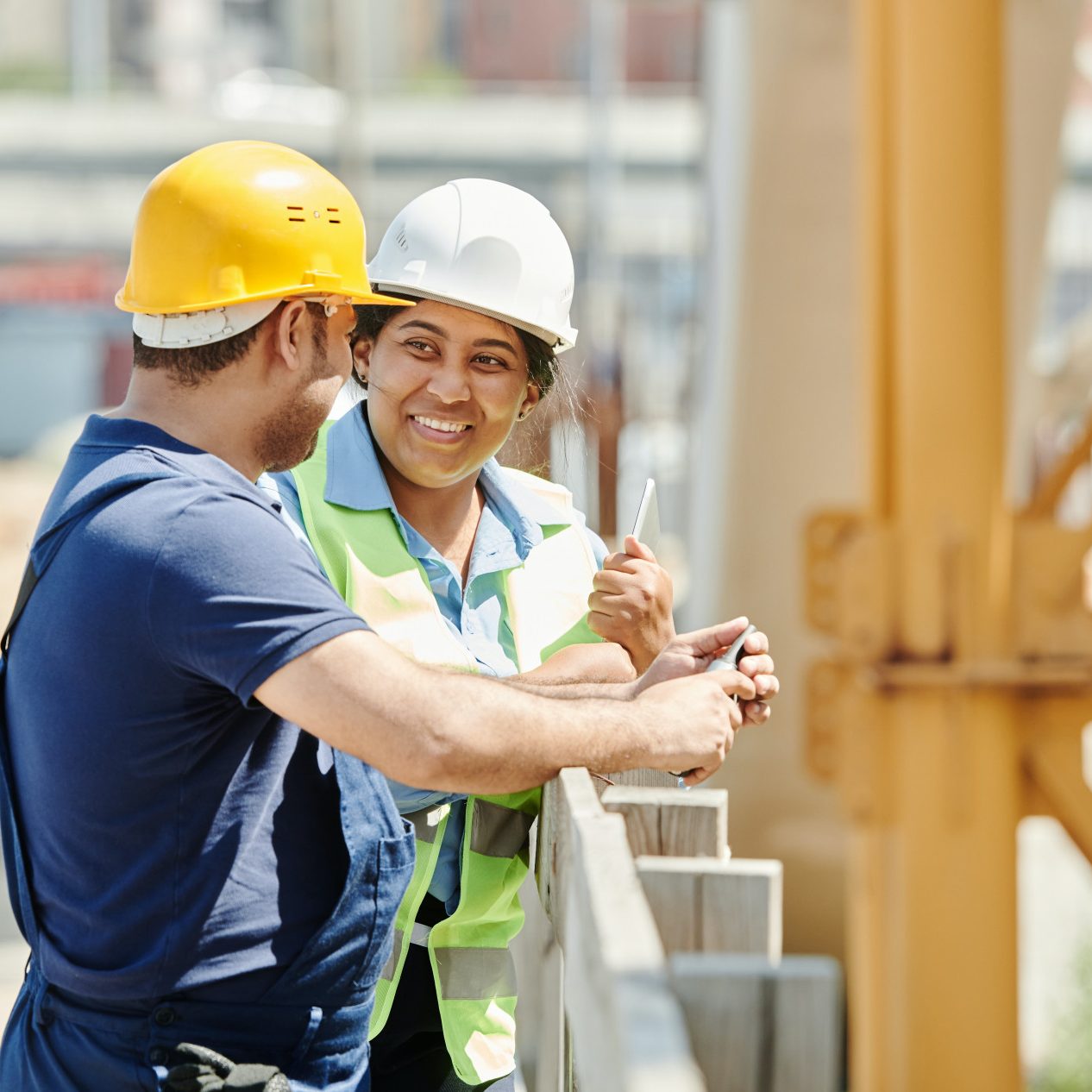 Two construction workers in hardhats conversing