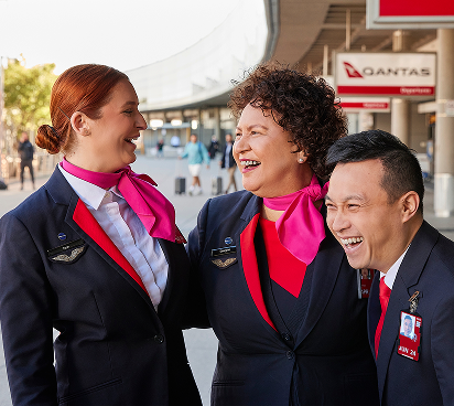 Three Qantas employees smiling and laughing at each other