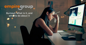 Image of woman sitting at desk experiencing burnout. empire group logo in the top left corner, with the title of the blog Burnout: What is it, and what to do about it, underneath it.