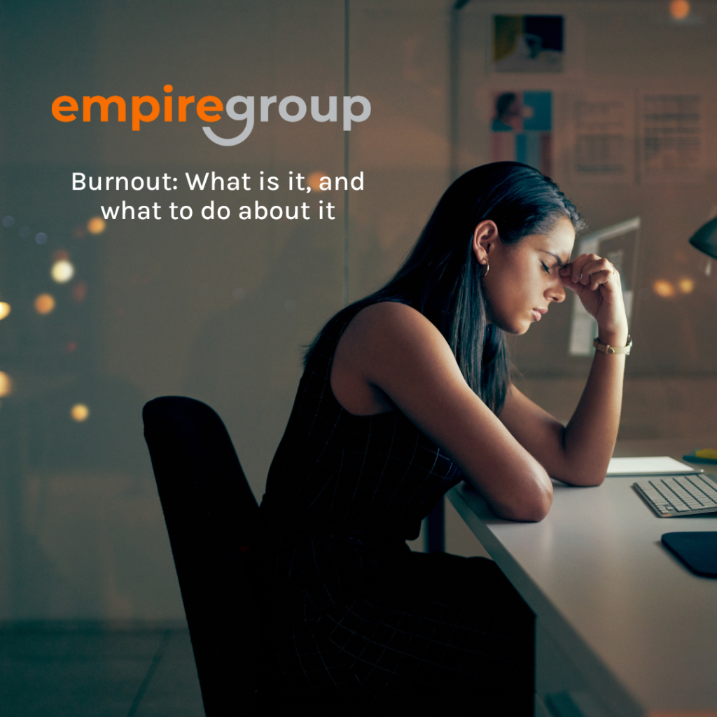 Image of woman sitting at desk experiencing burnout. empire group logo in the top left corner, with the title of the blog Burnout: What is it, and what to do about it, underneath it.