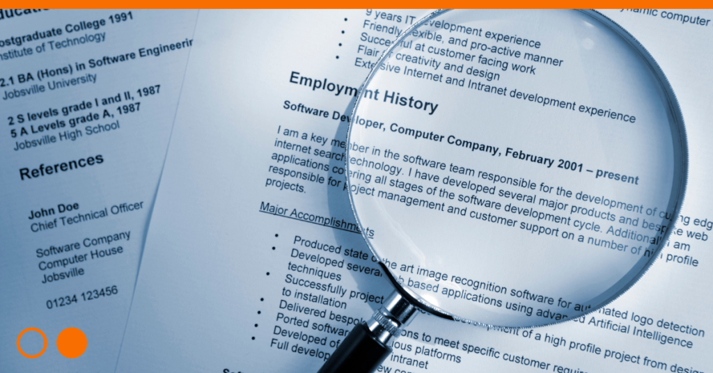 Magnifying glass sitting on top of a resume.