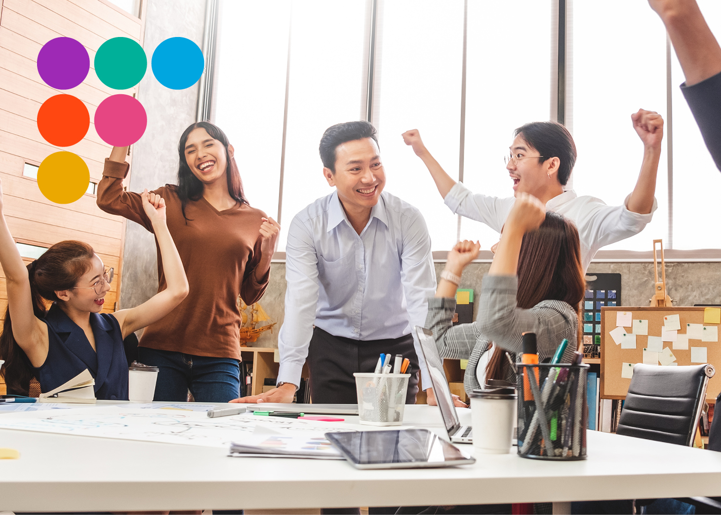 5 people at desk celebrating