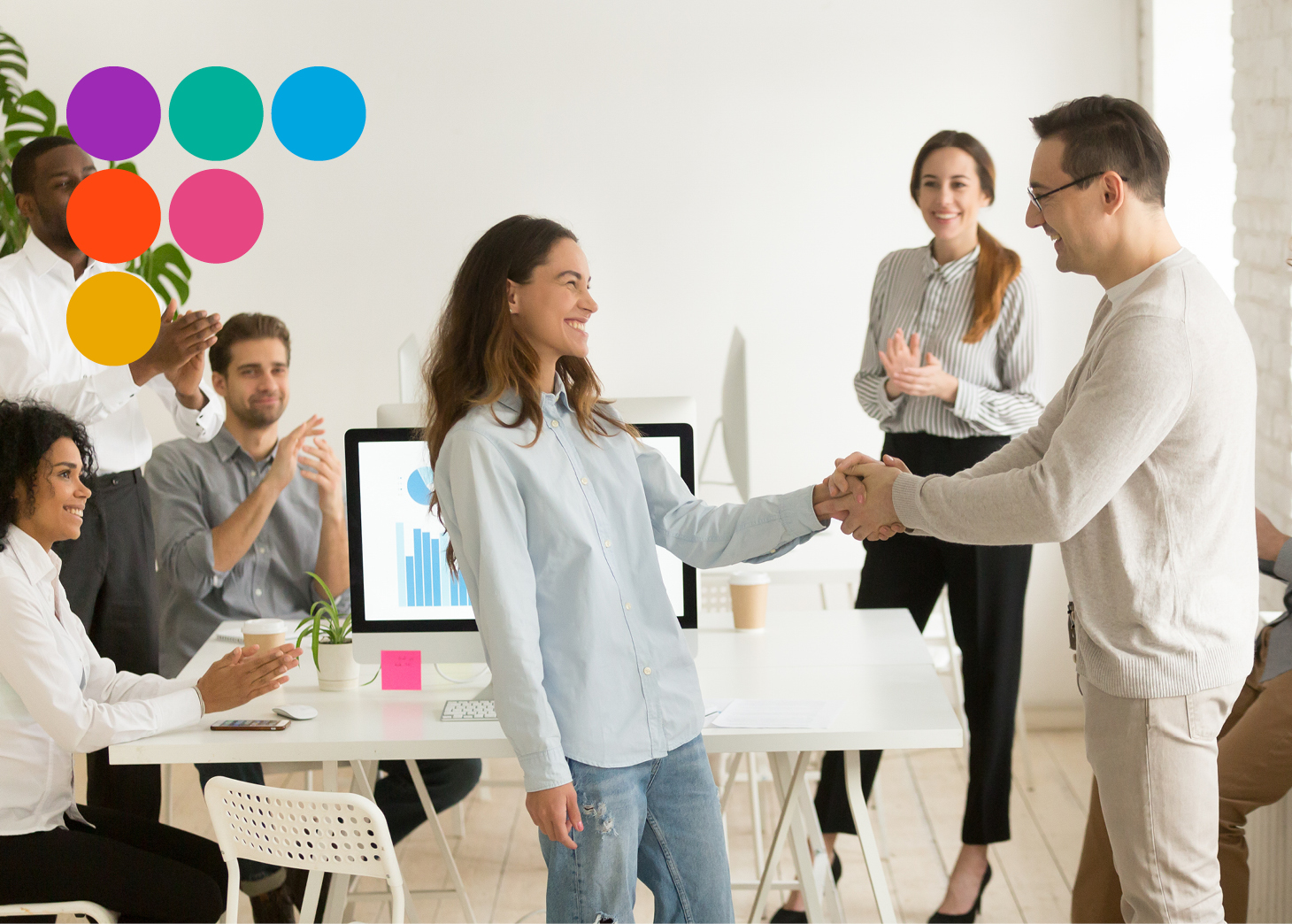 Man shaking hands with employer as other people clap