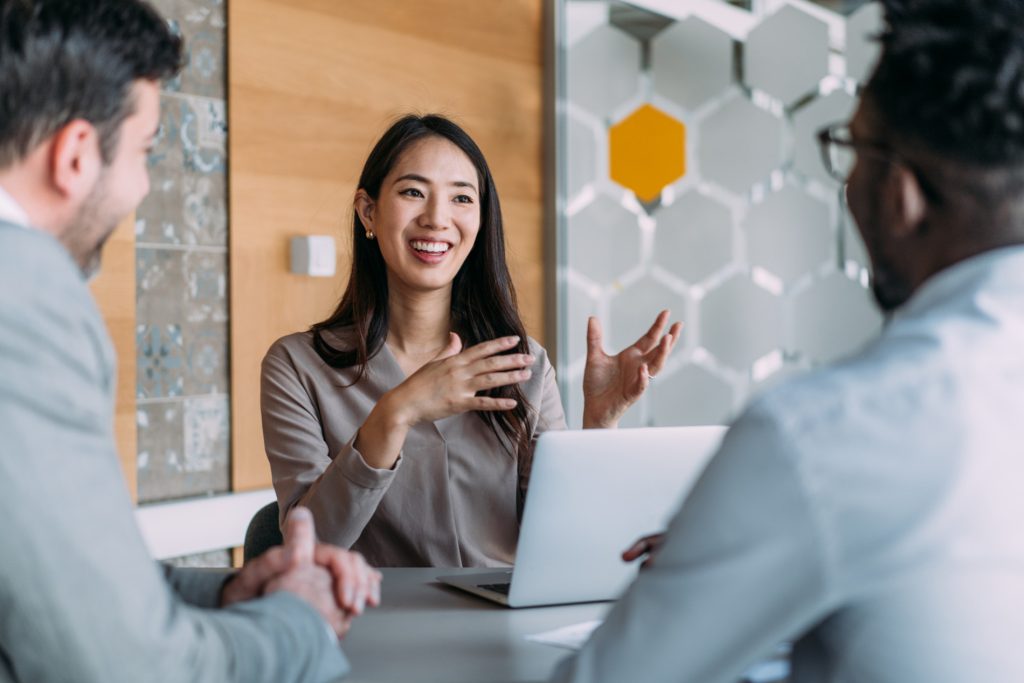 Insurance Underwriter reviewing client risk and policy options with colleagues during a meeting in an Australian office.