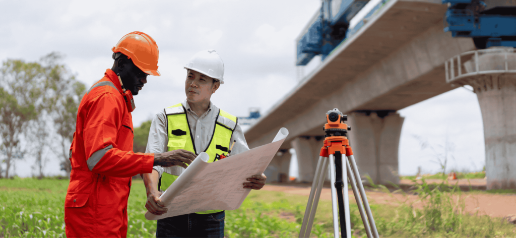 Civil Engineers analysing project plans and supervising bridge construction at an infrastructure site in Australia.