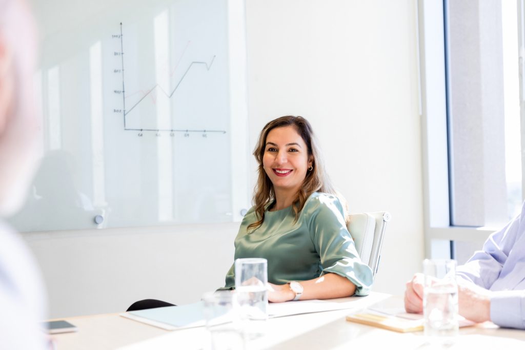 Administrator participating in a team meeting, reviewing documents and supporting office operations in a bright modern workspace.