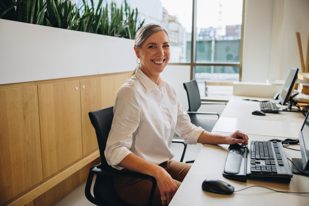 Executive Assistant sitting at her workstation, providing administrative support and managing office tasks in a contemporary workspace.