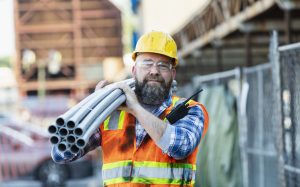 Tradesperson carrying piping on first day at new job.