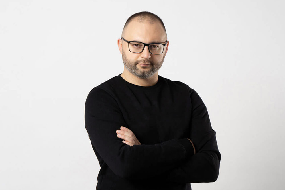 cover_man-with-black-rimmed-glasses-poses-with-his-arms-crossed-his-chest