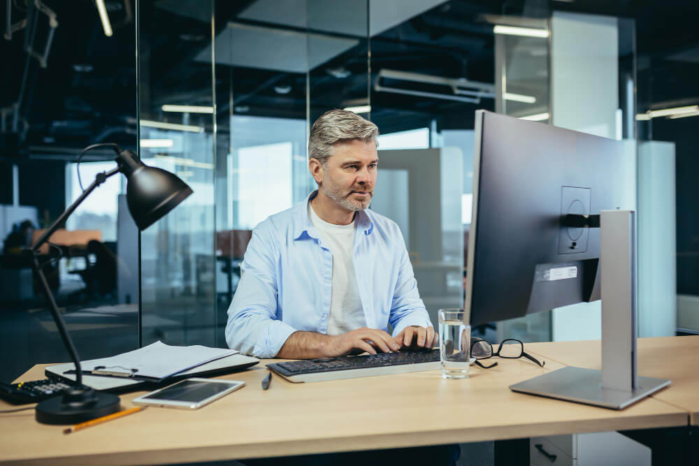 experienced worker greyhaired businessman works computer modern office