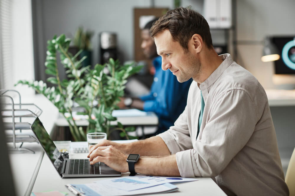 side view portrait smiling adult man using laptop while enjoying work office copy space