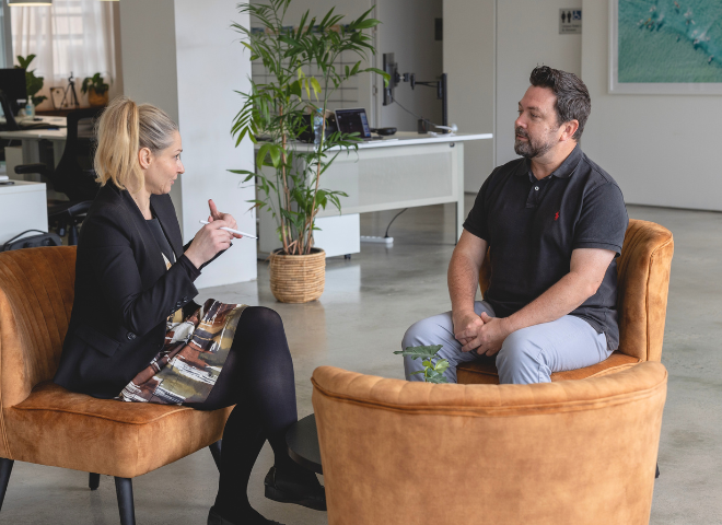 A man and woman sitting in chairs talking.