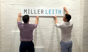 Two men putting up a Miller Leith sign