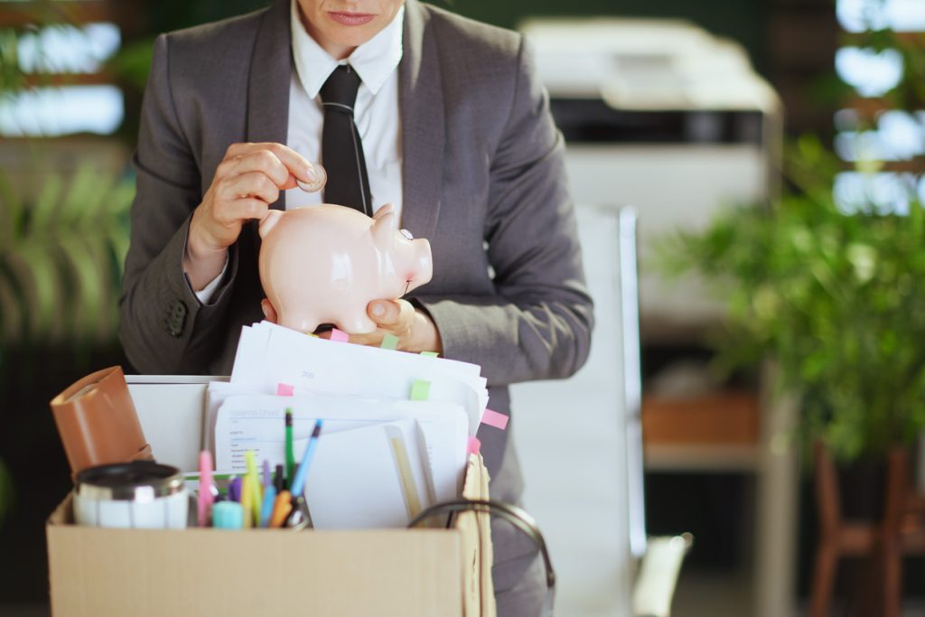 Modern woman worker in green office putting coin into piggy bank