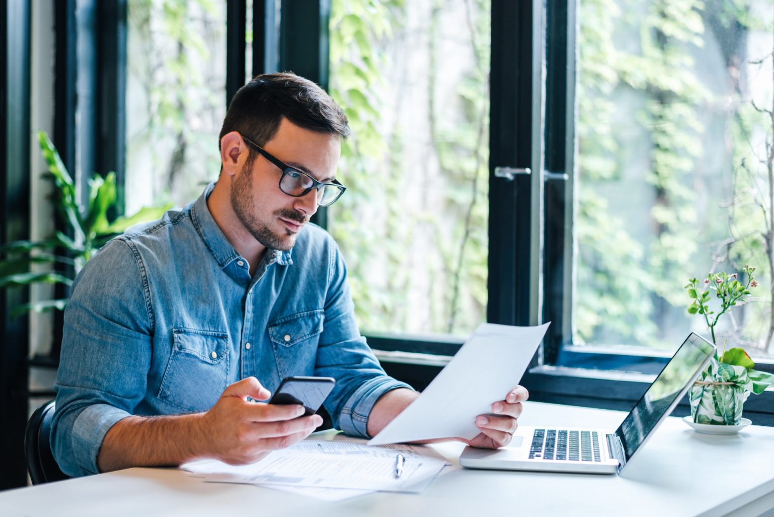 iStock-1343803257 Job seeker reviewing CV and application documents at a desk with laptop and phone, preparing to stand out in New Zealand trades and engineering job market.