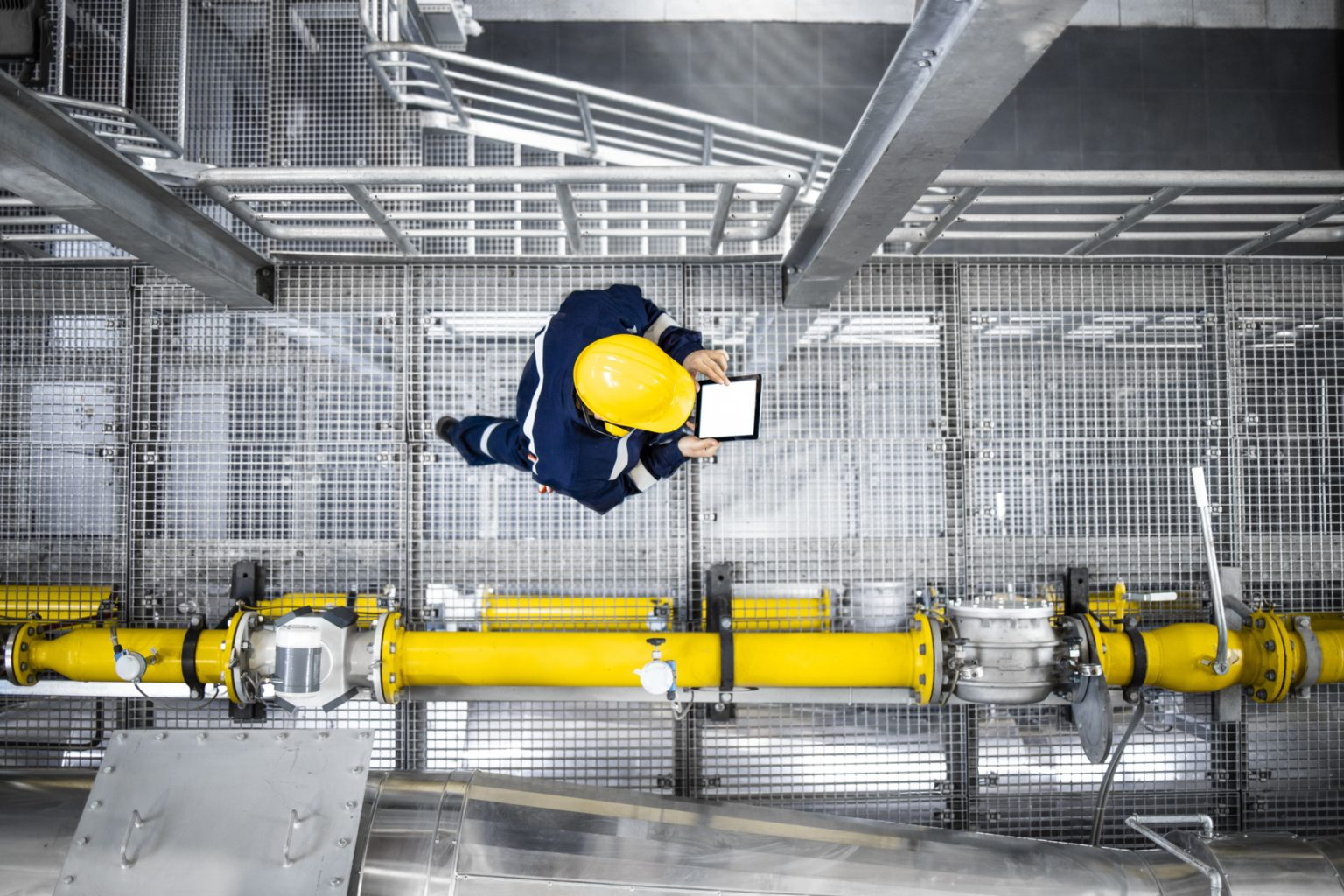 Petroleum Refinery worker Tradesperson in PPE working on industrial pipe system, representing new oil and gas job opportunities.