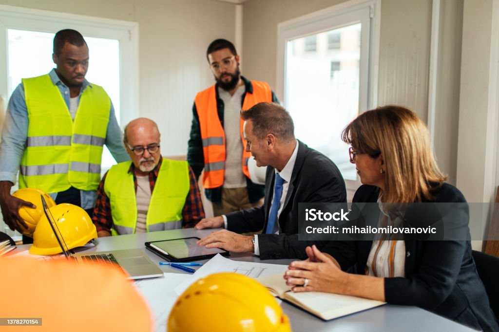 Construction workers having a meeting with the CEO in the office at the construction site